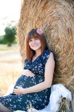 Foto Schwangere ist in einem Feld und lächelt , Blume im Haar