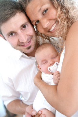 Foto Mutter und Vater umarmen ihr Baby und lachen in die Kamera