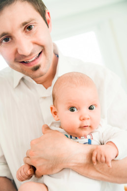 Foto Vater hält Baby auf de Arm und lacht