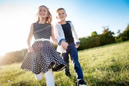 Geschwisterfoto , Bruder und Schwester laufen über eine Wiese