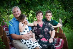 Familienfoto, Oma und Opa sitzen mit Enkeln auf einer Bank