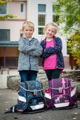 Foto Geschwister auf dem Schulhof mit Schulranzen