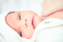 Neugeborenes Baby schaut mit großen blauen Augen