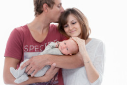 Foto Vater hält Baby auf dem Arm und küsst Mutter, junge Familie