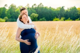 Schwangerschaftsfotos in Pforzheim Wurmberg, Schwangere und ihr Partner stehen mit geschlossenen Augen auf einem Feld, Sommerstimmung