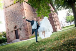 Foto Brautpaar vor Kirche in Birkenfeld freut sich und springt