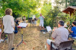 Orchesterleiter Thomas Meyer probt mit einer Bläsergruppen im sommerlichen Garten - Fotoprojekt Nur-so-halb von Stefanie Morlok Fotografin
